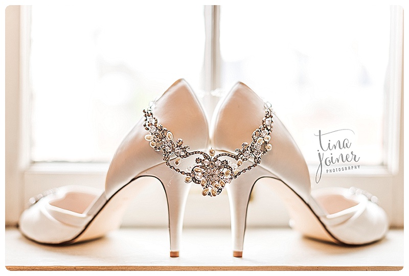 Stunning detail photograph of brides diamond and pearl necklace and her satin shoes