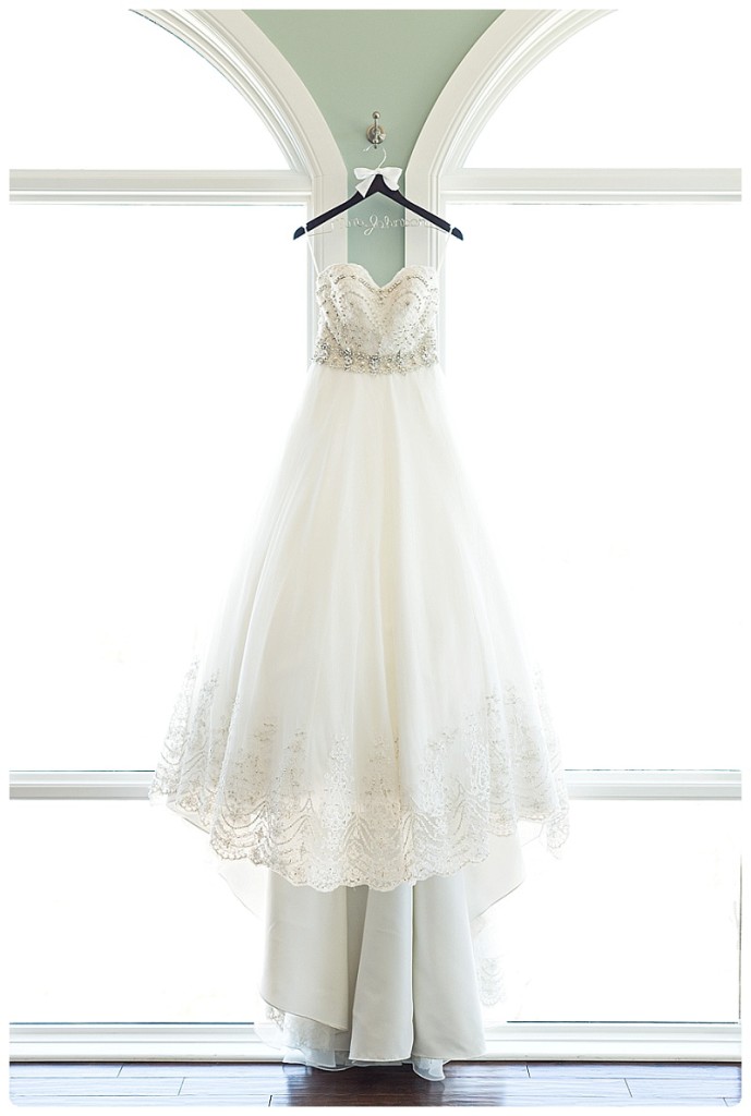 Brides wedding dress hanging between two large windows at The Pinery
