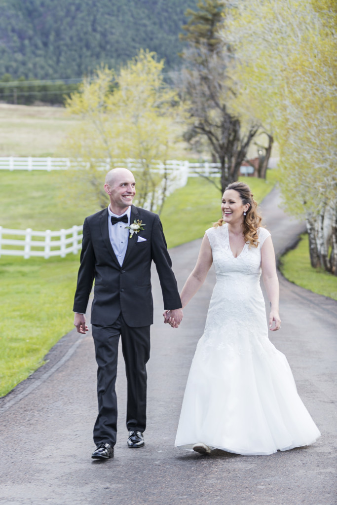 Bride and groom walk holding hands laughing and talking