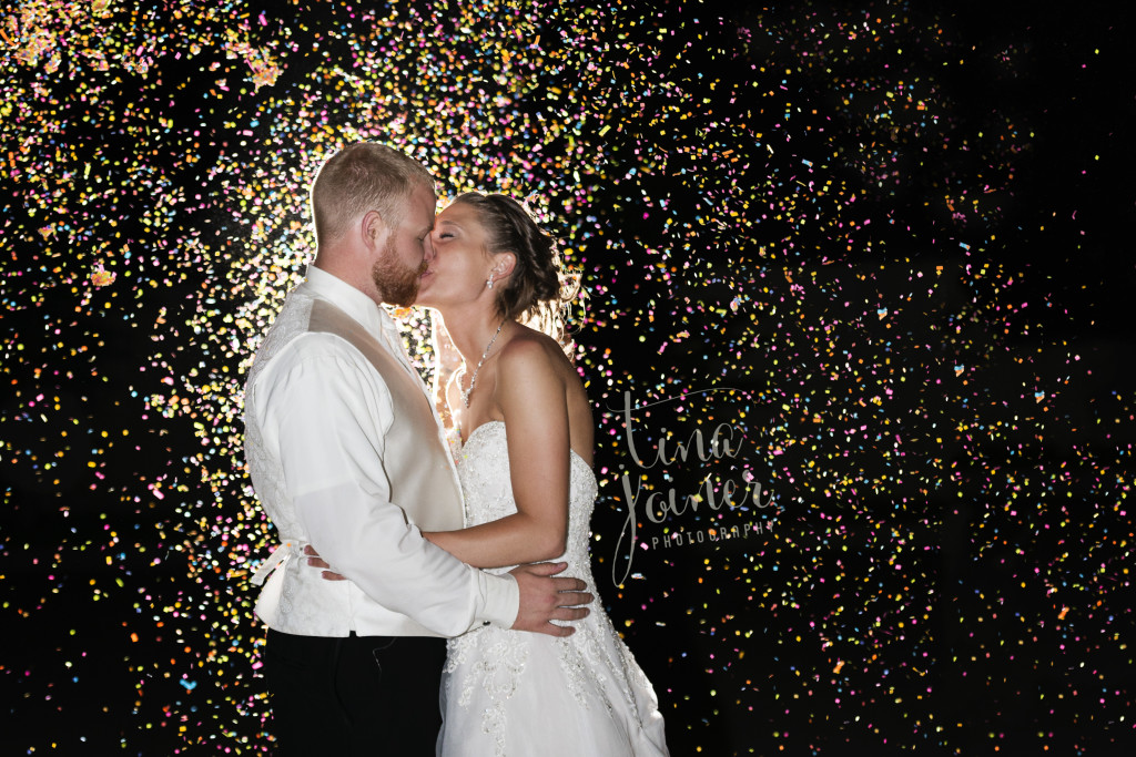 Amazing night shot of bride and groom kissing with confetti lit up and sparkling, a dynamic and unique photo
