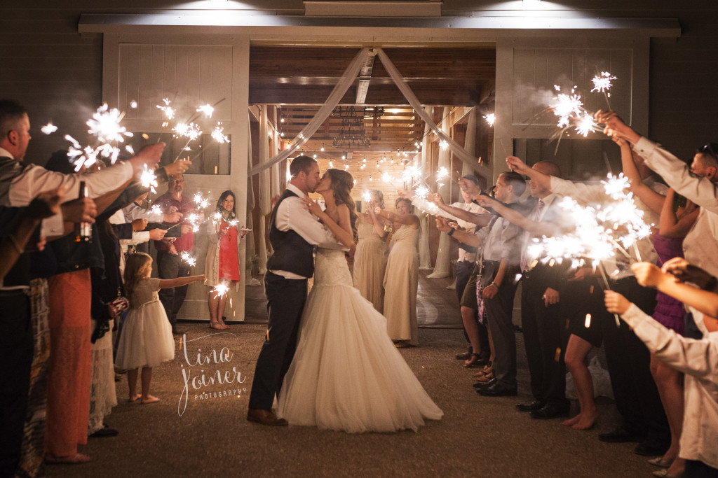 Sparkler exit at Flying Horse Ranch, couple stops to kiss while their guests cheer with bright sparklers