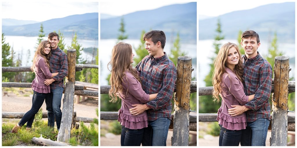 Stephanie and Tate cuddling by a rustic fence with a lake and mountains in the background