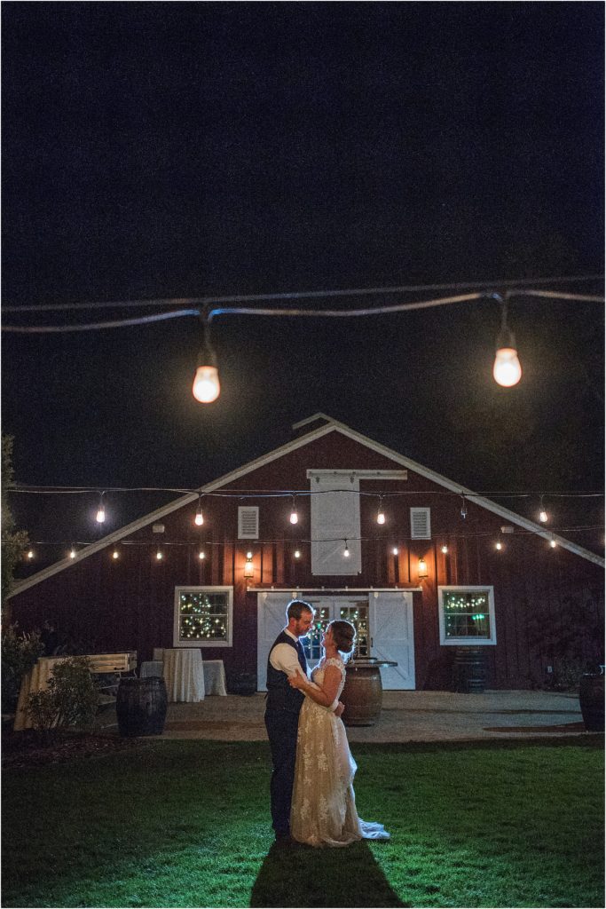 beautiful night shot in front of barn of bride and groom with back lighting