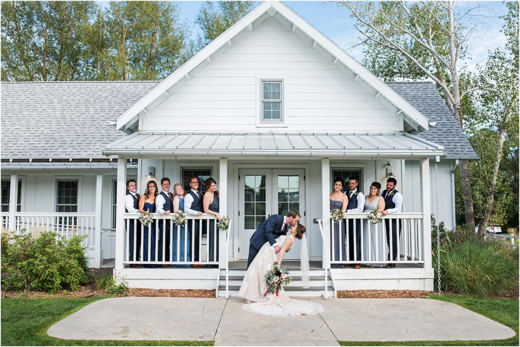 Groom dips and kisses bride on the forehead with bridal party looking on with smiles at the bridal cottage at the barn at raccoon creek