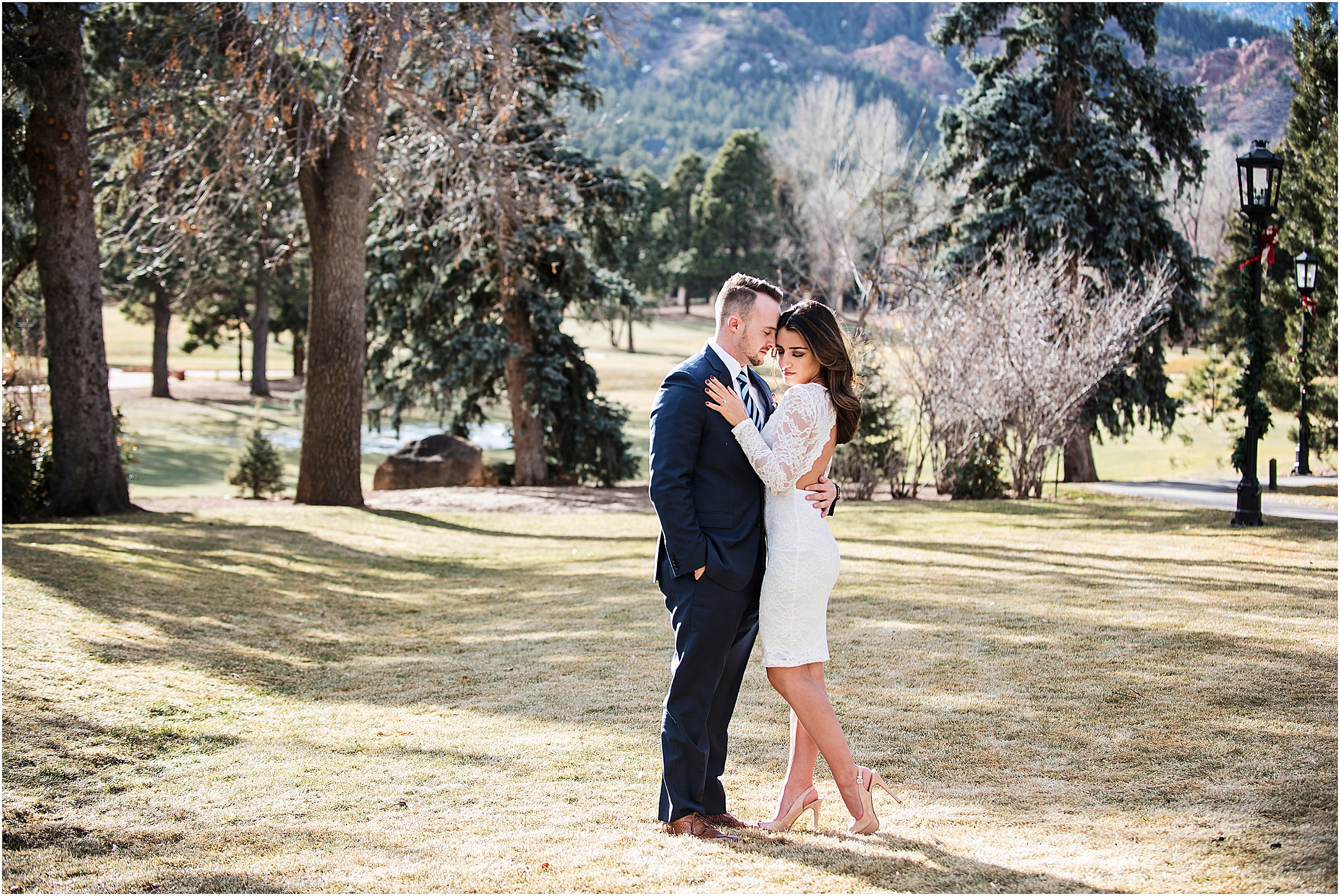 Man and woman embracing in the open space behind the broadmoor, he is kissing her temple and she has her eyes closed