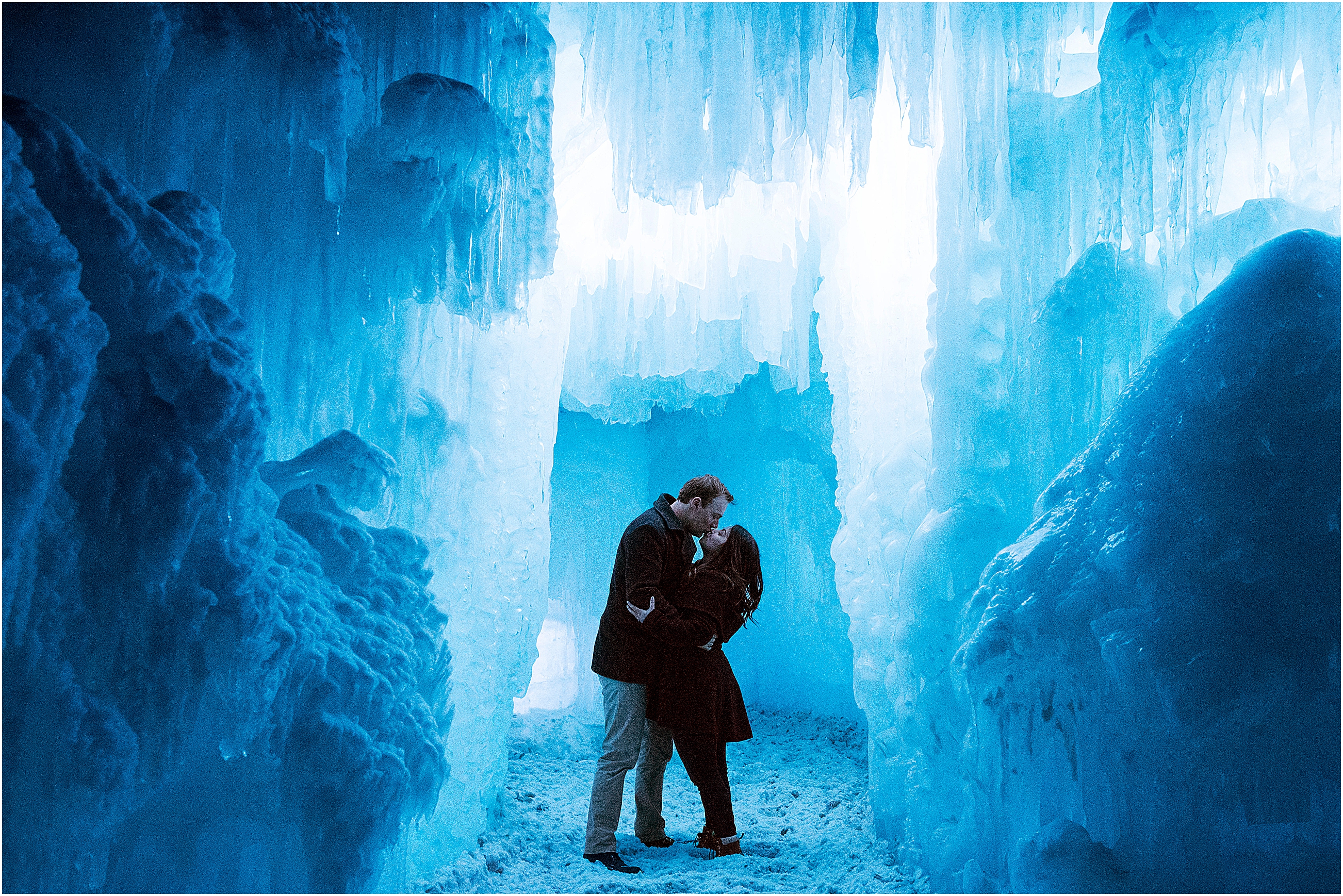 couple kissing and embracing in an ice cave lit up with blue lights at dillon ice castles