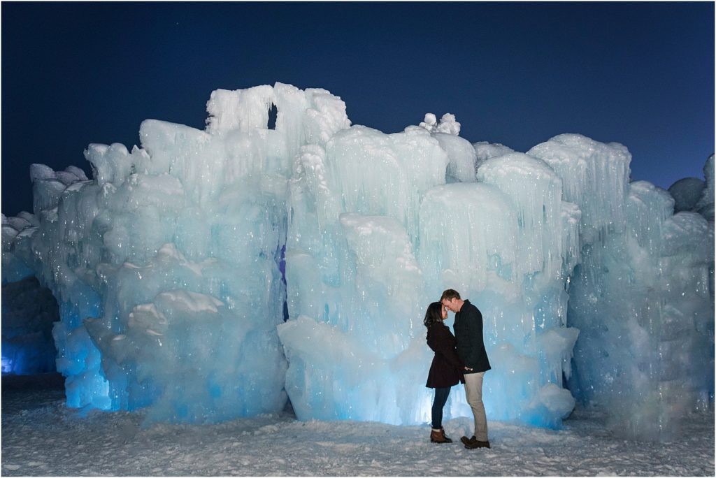 man and woman with their foreheads together and smiling at each other with snow and ice behind them