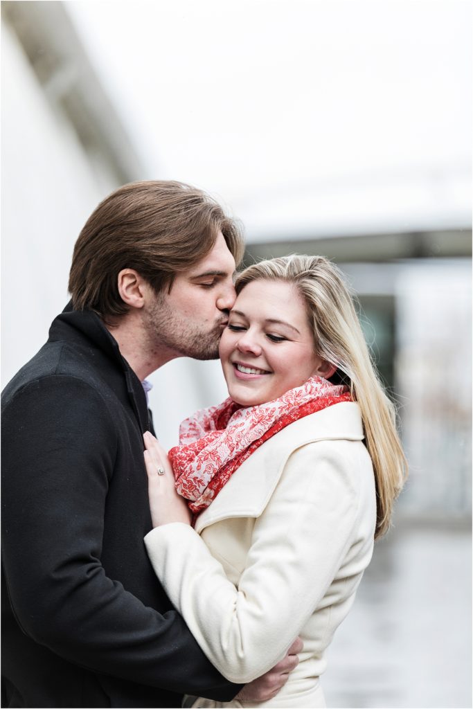 Rachel has her eyes closed while Mark kisses her temple in this downtown Denver engagement session]