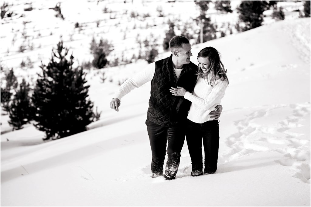 Couple walk and laugh in the snow, snow is deep, up to their knees