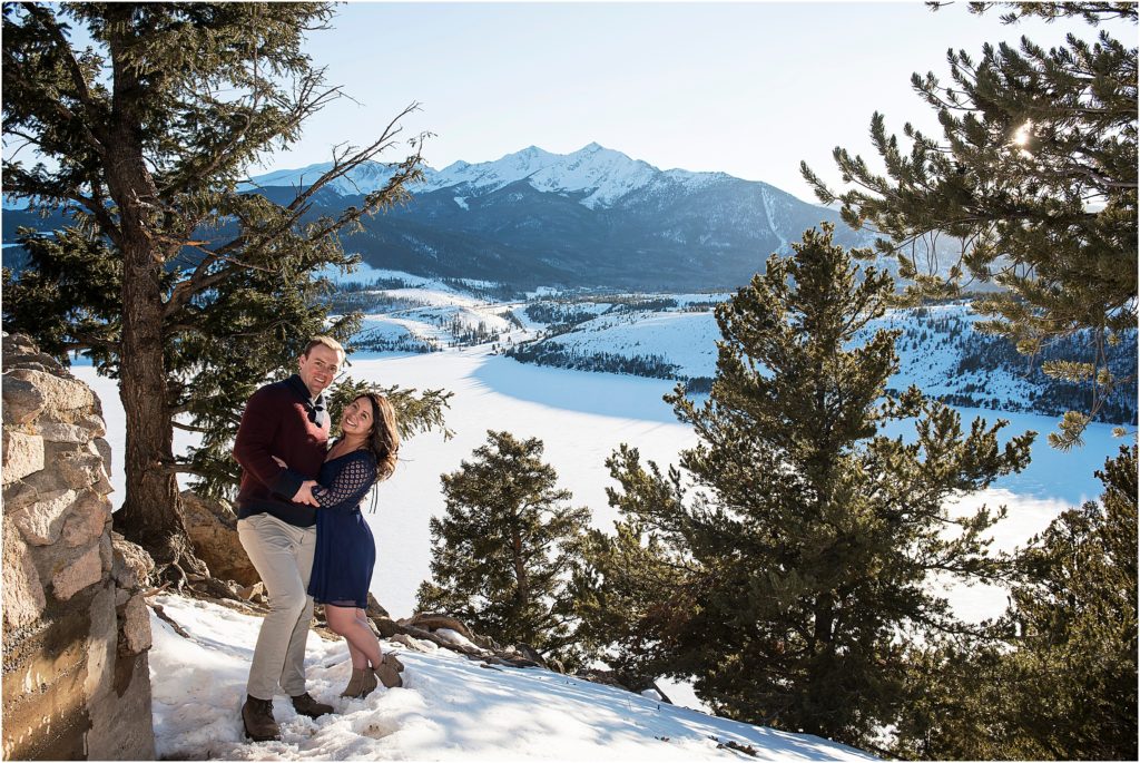 engaged couple at sapphire point with beautiful mountain view, they are smiling at the camera and embracing