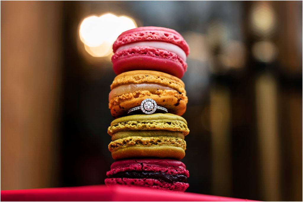 Assorted colors of macarons stacked with engagement ring in the center