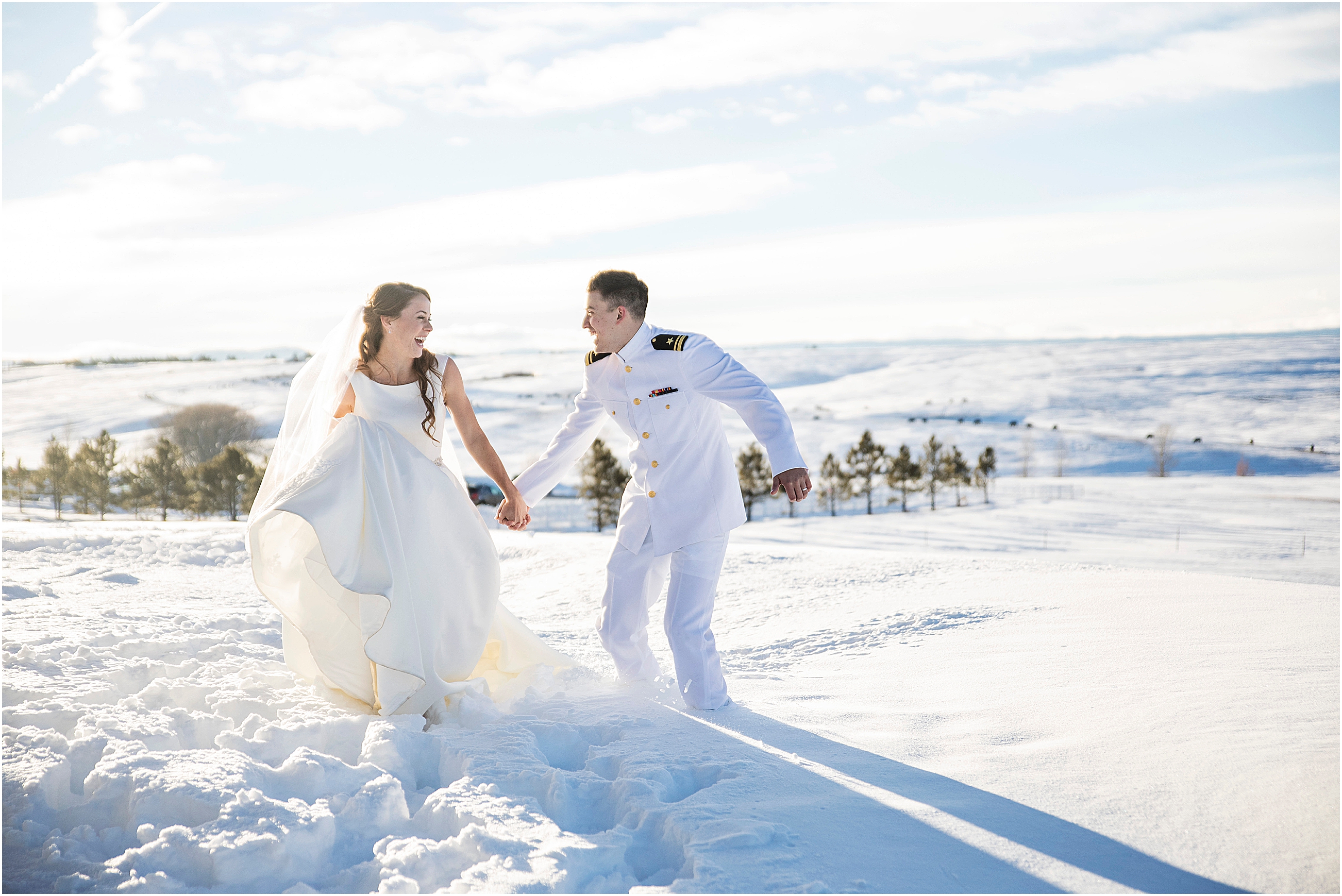 Bride and groom frolic in the deep snow in a field at a winter wedding, groom is in Navy dress whites