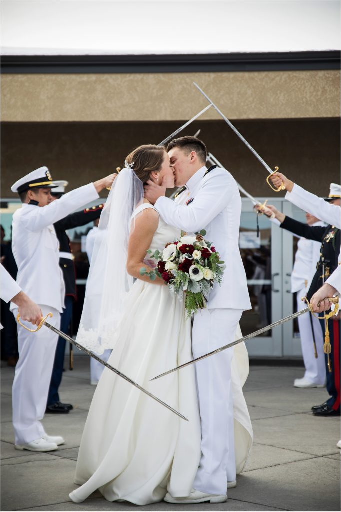 bride and groom embrace and kiss at the sword arch exit outside of church before going to reception, groom is wearing Navy dress uniform