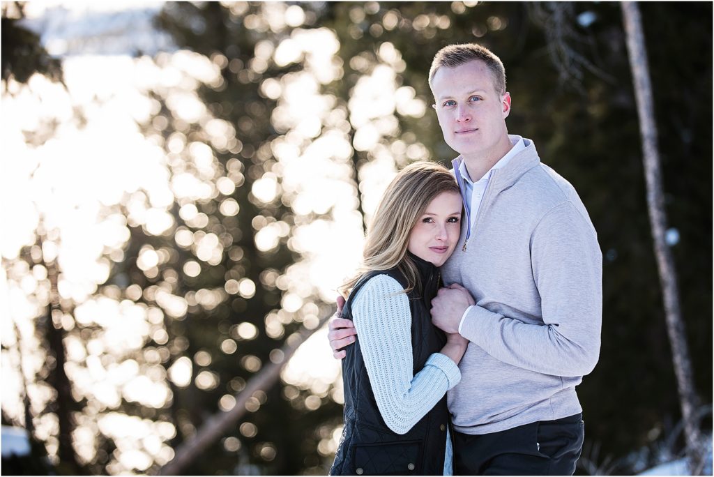 couple embraces and looks at camera in a forested area of Breckenridge, Colorado