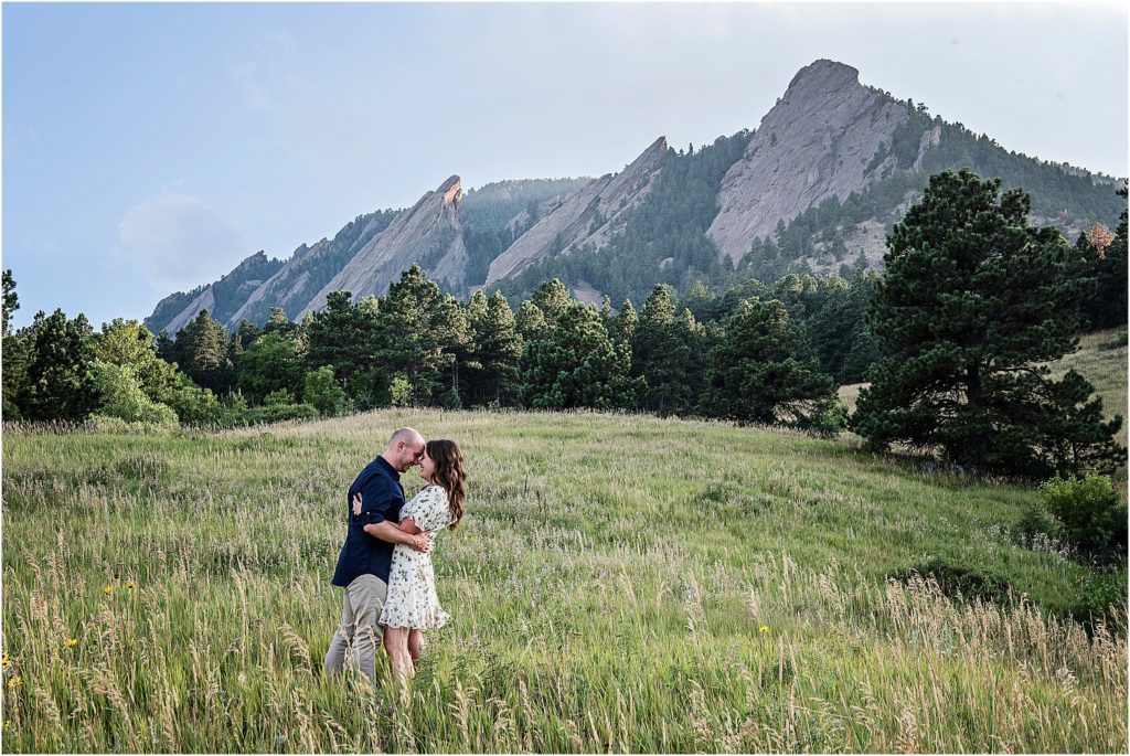 Couple hold each other romantically with foreheads together with Chautauqua Flatirons in Boulder behind them