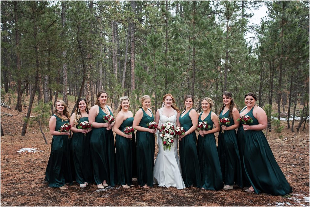 Cassidy stands with her bridesmaids, who are wearing hunter green, dark green, forest green, at her winter wedding during the holiday season