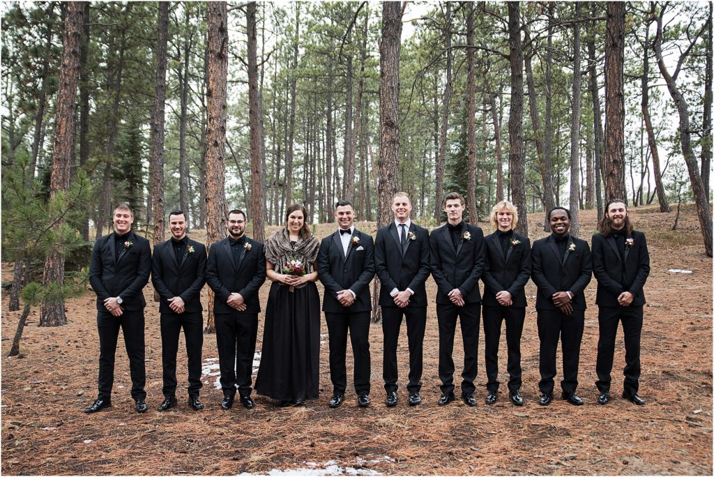Groom and Groomsmen plus one Lady in a forest at wintertime wearing black