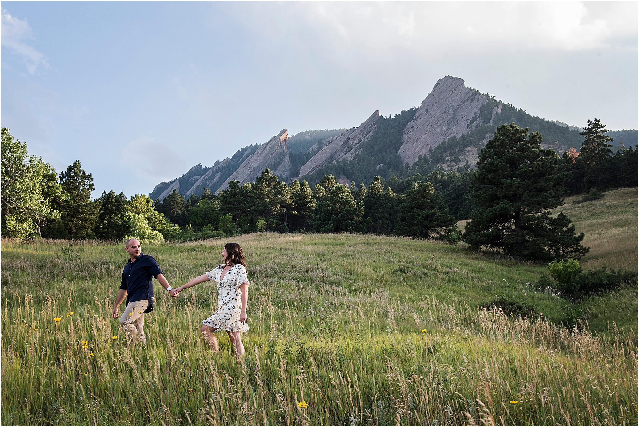 Man and woman walking in a meadow with Chautauqua Flatirons behind them