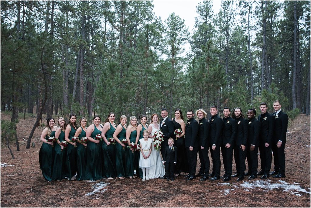 Cassidy and Jeff and their wedding party, Altogether 22 people, bridesmaids are wearing forest green and the groomsmen and grooms lady are wearing black