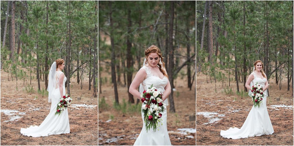 Cassidy stands holding her bouquet in her wedding dress in the forest at wintertime for her Christmas wedding