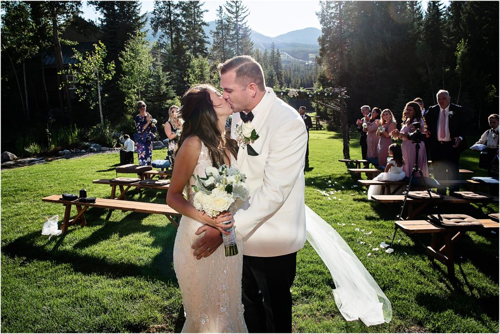 Steve and Olivia share a kiss while their wedding guests celebrate at their small ceremony in Breckenridge.