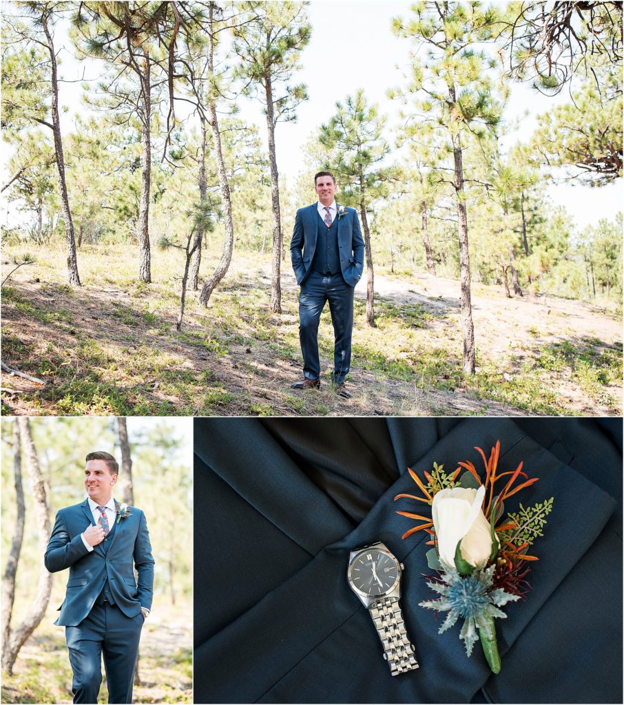 groom details include a white rose boutonniere and a bold floral tie. Groom stands among trees in the moments before his first look.