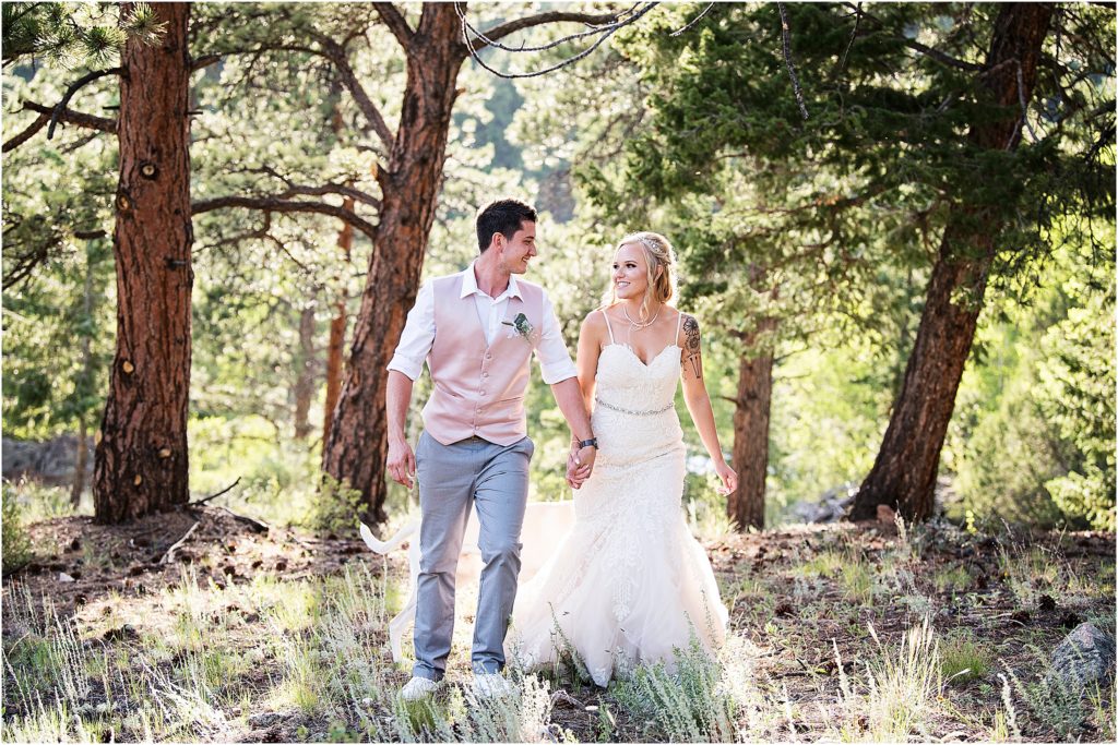 Bride and groom walk through the trees at their colorado wedding during covid