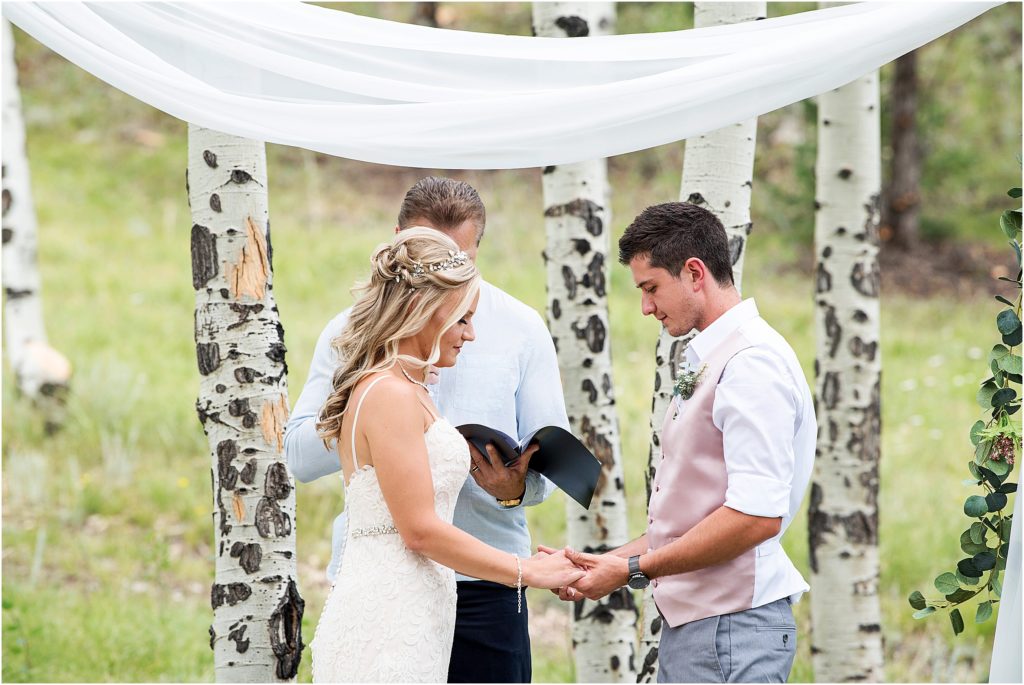Derek and Breanda hold hands during prayer during outdoor ceremony during Covid