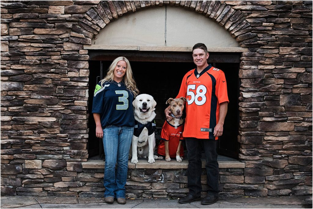 Jordan and Brian stand with their dogs at the outdoor fireplace at Spruce Mountain Ranch in Larkspur Colorado.
