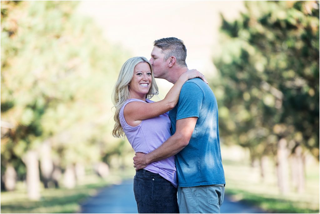 Jordan smiles brilliantly while Brian kisses her temple at the main entrance at Spruce Mountain Ranch near Colorado Springs