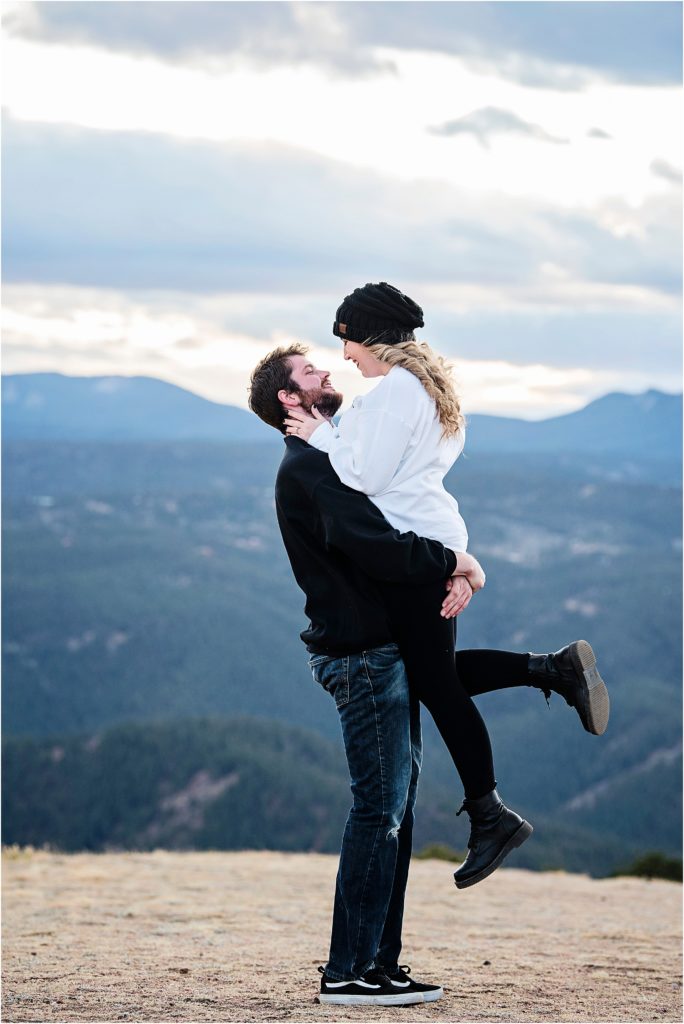 Andrew lifts Martha and they smile at each other while in the Colorado Rocky Mountains