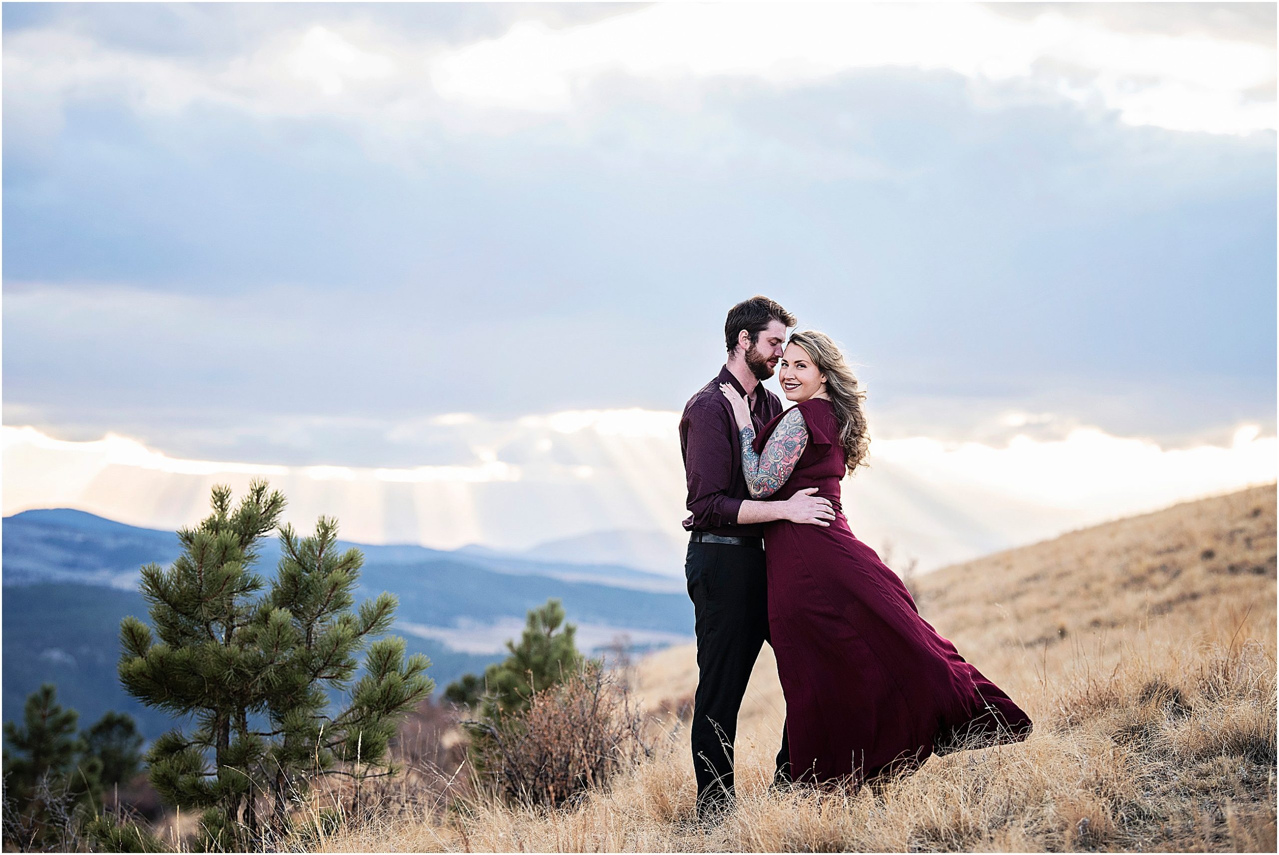 Martha's dress catches a breeze as Andrew embraces her in the mountains near Colorado Springs at sunset