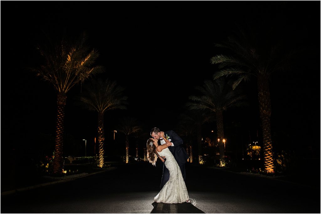 Bride and groom at night with palm trees lit up
