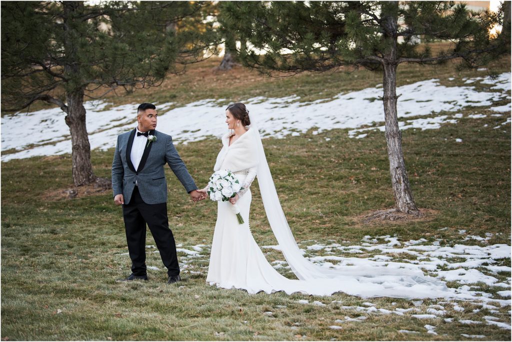 Groom leads bride by the hand in the snow during their winter wedding in Denver Colorado