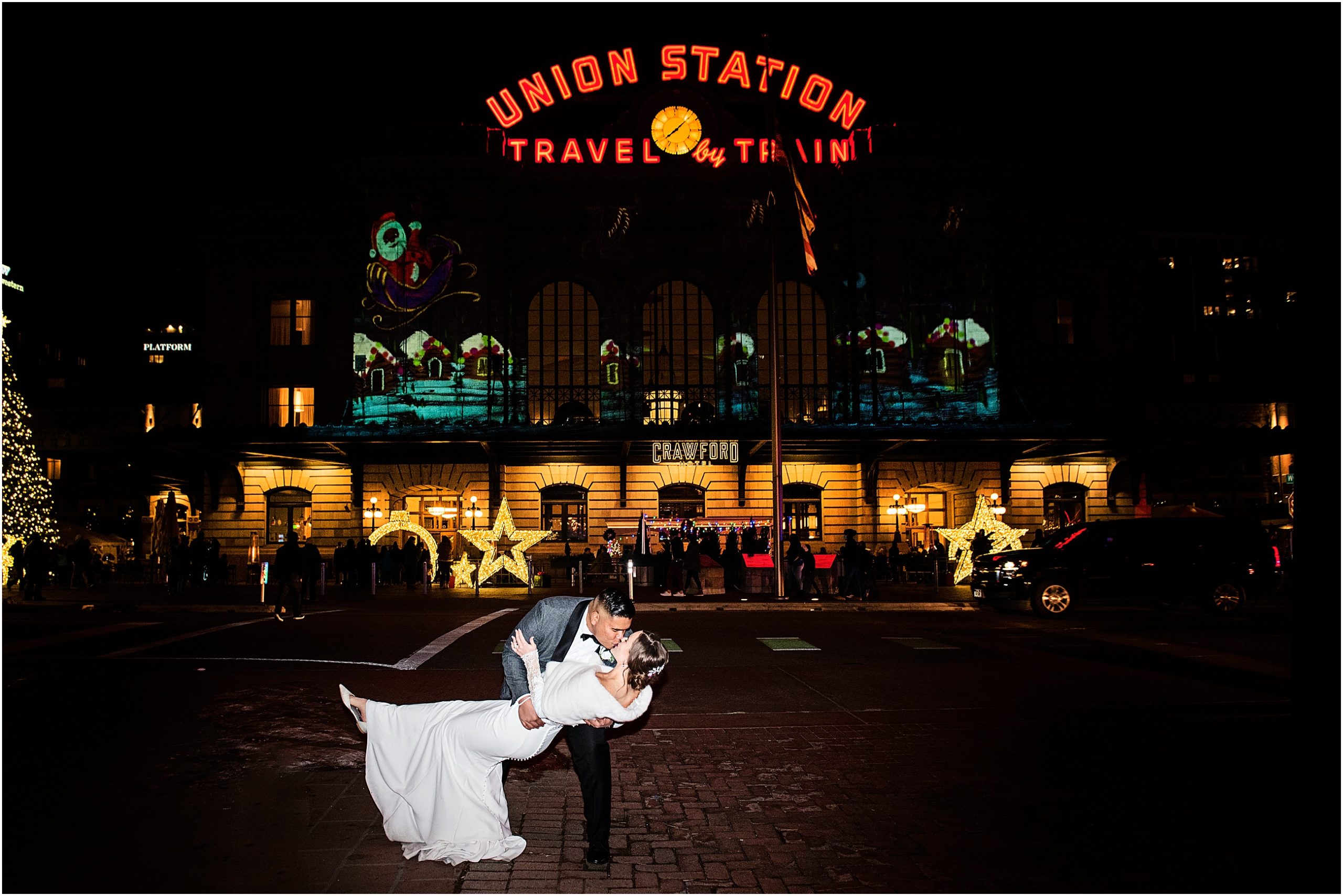 Groom dips bride and kisses her in front of Union Station in Denver at Christmas