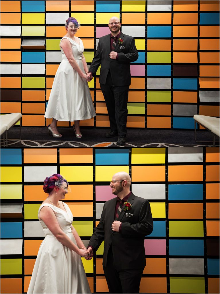 Couple stand in front of colorful wall at the Curtis hotel in Denver.