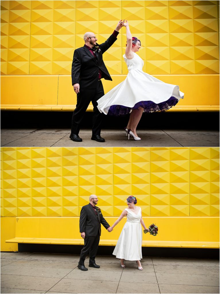 Denver couple dances in front of a solid yellow wall during their downtown wedding at the Curtis Hotel