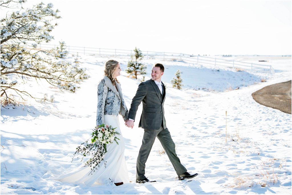 bride and groom walking together through the snow after their wedding ceremony