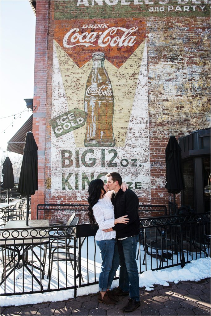 Couple embracing and kissing in downtown Fort Collins during their engagement photos