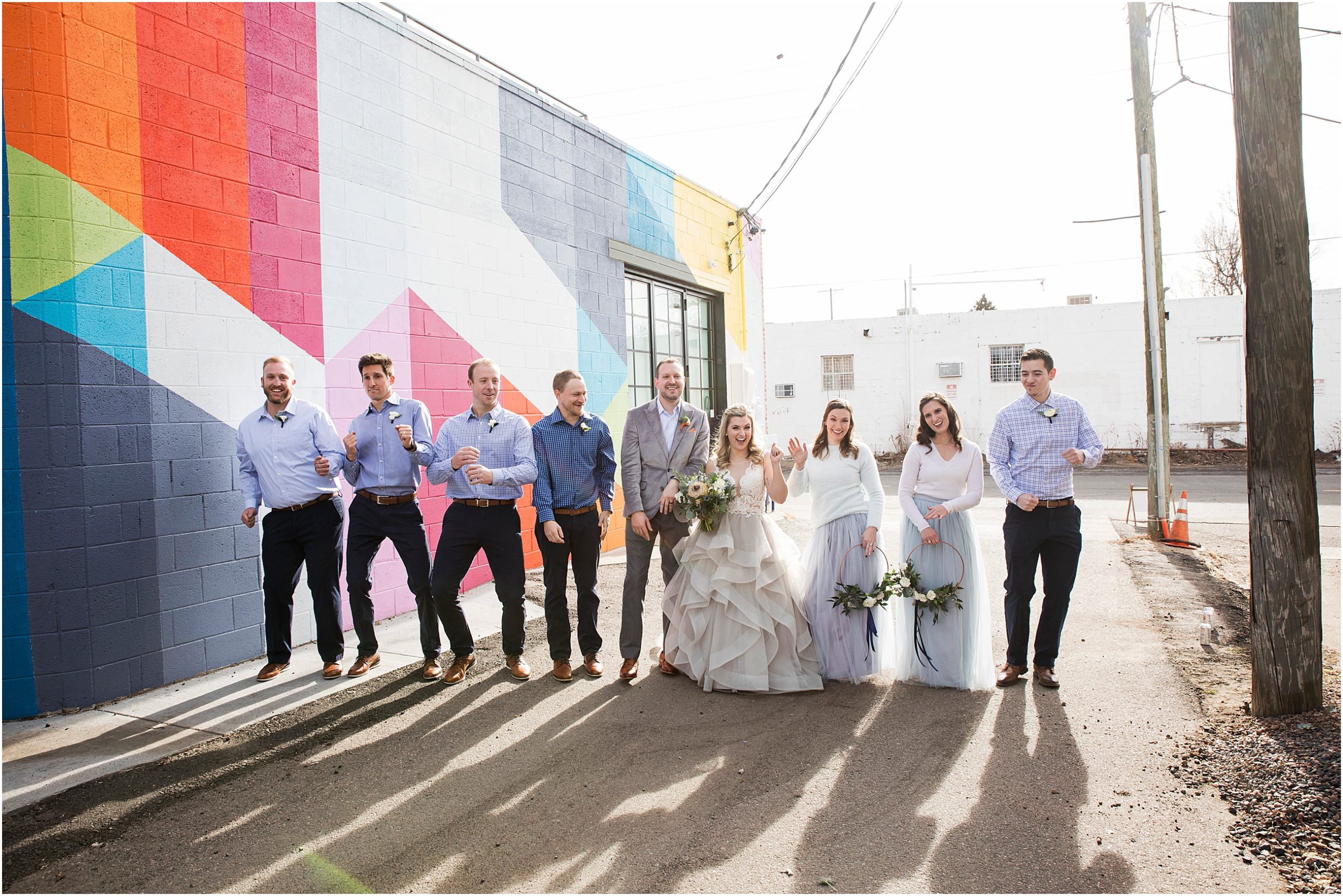 Wedding party dances near a brightly colored wall at an art gallery in Denver