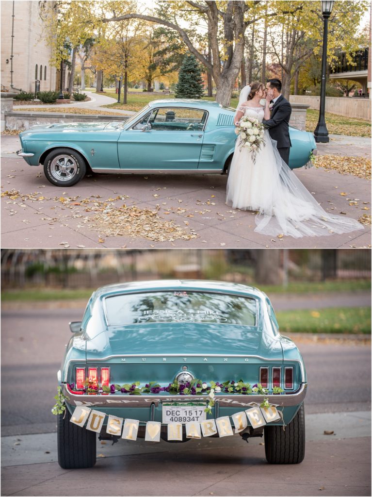 A happy newlywed couple poses in front of a teal Ford Mustang dressed with plumb purple flowers on a beautiful Fall day