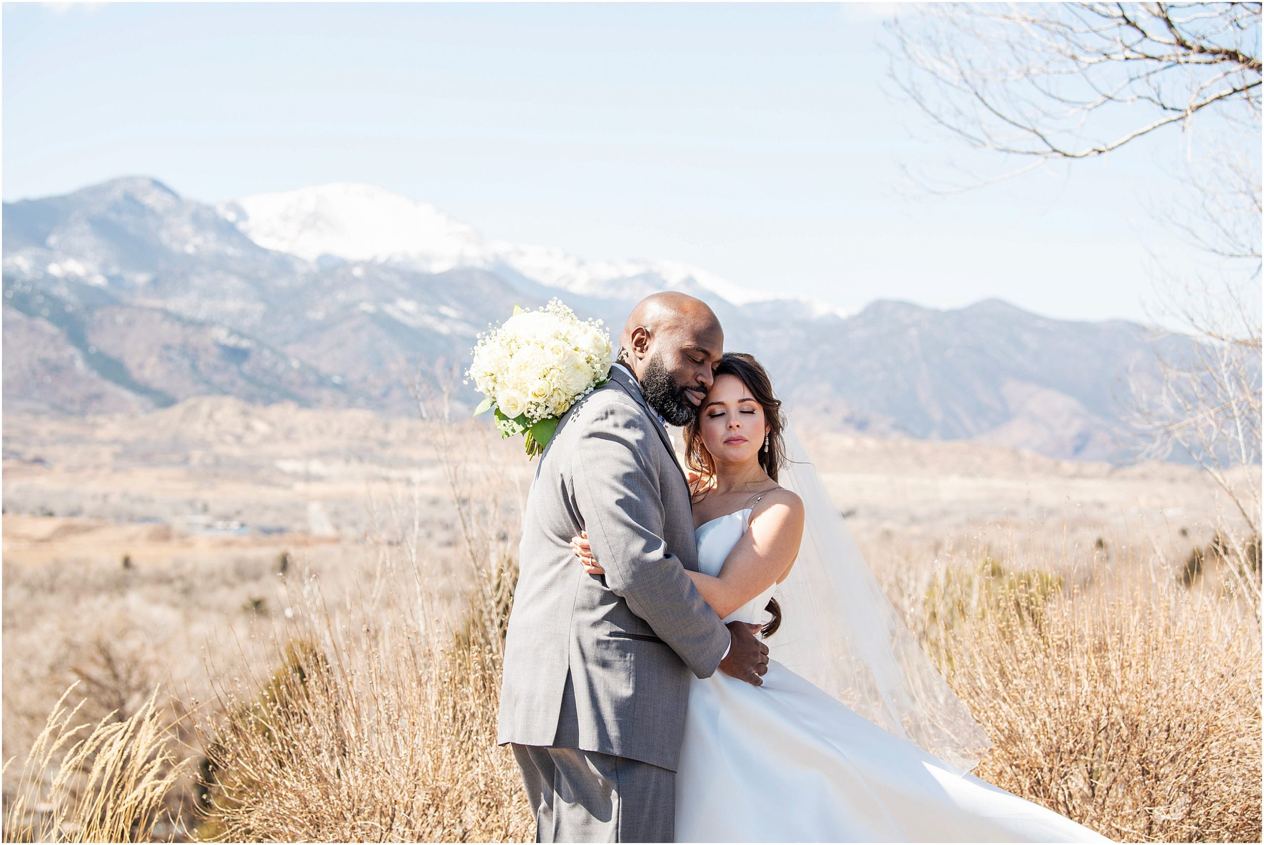 Bride and groom embrace on their wedding day with mountain views behind them.