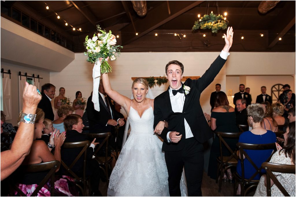 Bride and groom celebrate as they are announced at their reception for the first time as husband and wife their arms are in the air as the bride holds up her beautiful bouquet made by florist Cusick Creative