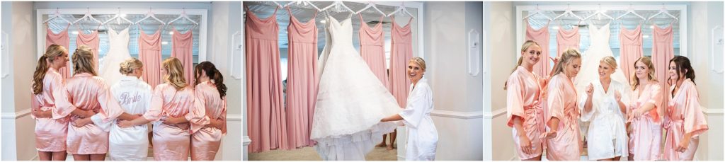 Bride poses in silk robe with her bridesmaids in front of her lace ballroom gown blush bridesmaids dresses are hung next to the bride's in front of a large mirror the bride gushes in bridal suite as she holds her wedding dress four bridesmaids are dancing with the bride