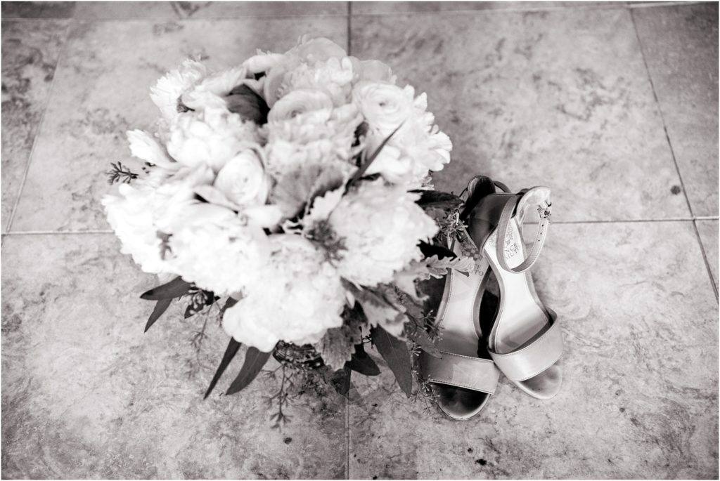 The simple elegance of the white peony bouquet and bride's shoes is captured in this back and white photo