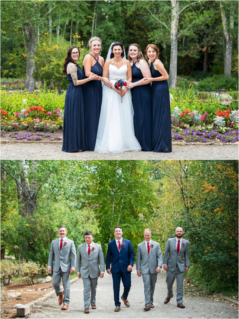 Bridesmaids pose with the bride in floor length navy blue dresses, the groomsmen pose with the groom in grey suits the groom is in a navy blue suit with a red tie