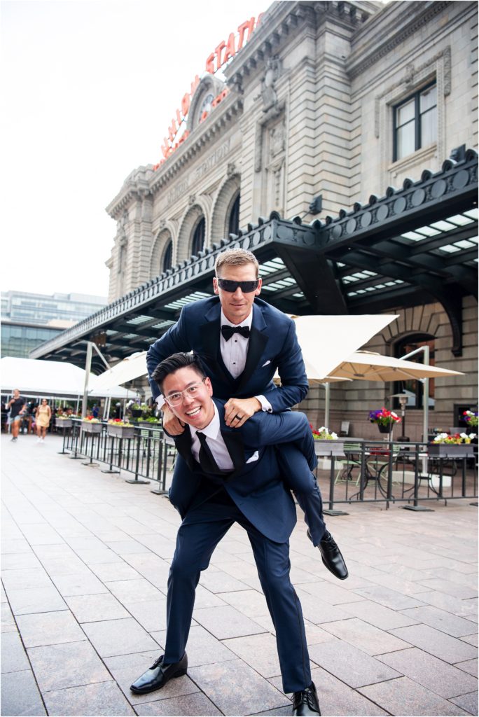 Outdoor wedding photograph of the groom and a groomsman having fun outside of Union Station in Denver Colorado