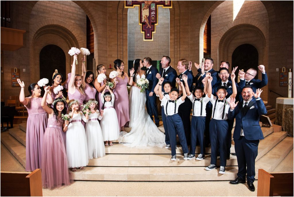 Wedding party celebrates as they surround the bride and groom at this indoor Colorado wedding