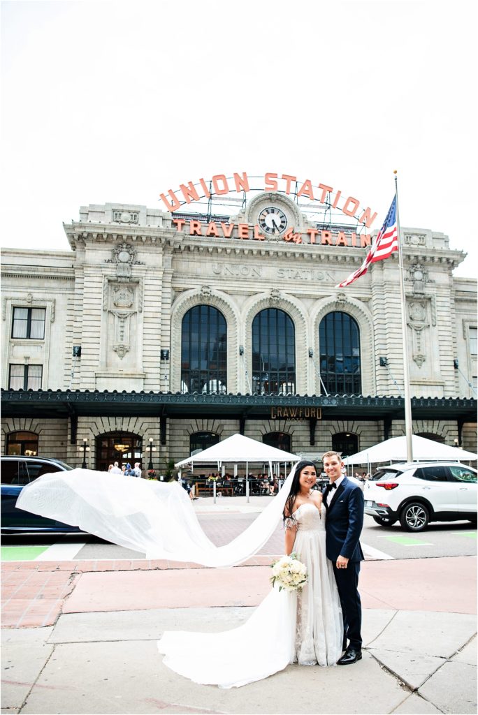 Urban Colorado wedding in downtown Denver Colorado; bride's veil swoops gracefully in front of Union Station