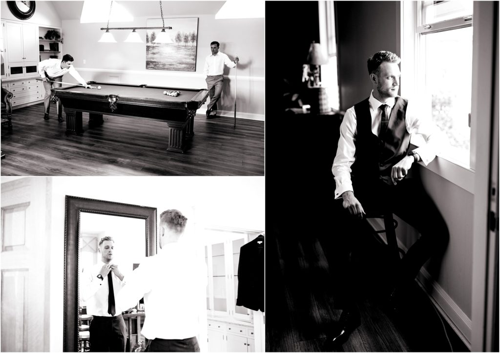 Groom in black vest, black tie and white shirt has a masculine look, his groomsmen are having fun playing a game of pool in the groom's quarters, groom poses in front of full length mirror